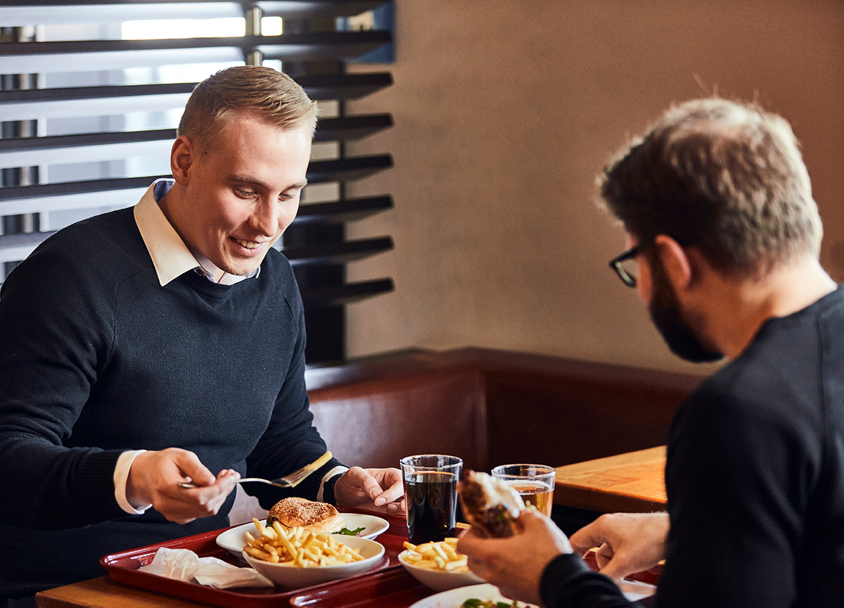 Zwei Männer essen gemeinsam Burger und Pommes in einem Jim Block Restaurant