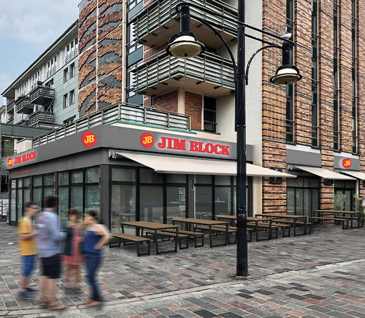 Visualisierung der zukünftigen Außenfassade des neuen Jim Block Restaurants in Rostock mit moderner Glasfront, Sitzbereich im Freien und städtischem Umfeld.