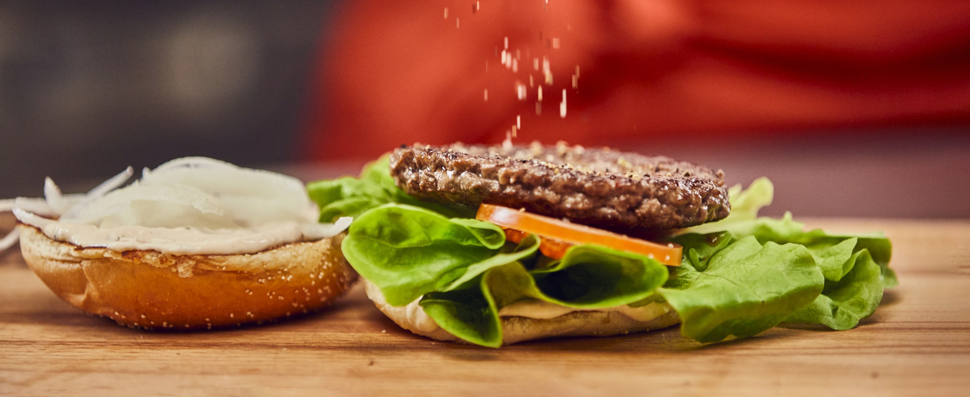 Ein Burger wird zusammen gebaut und gewürzt